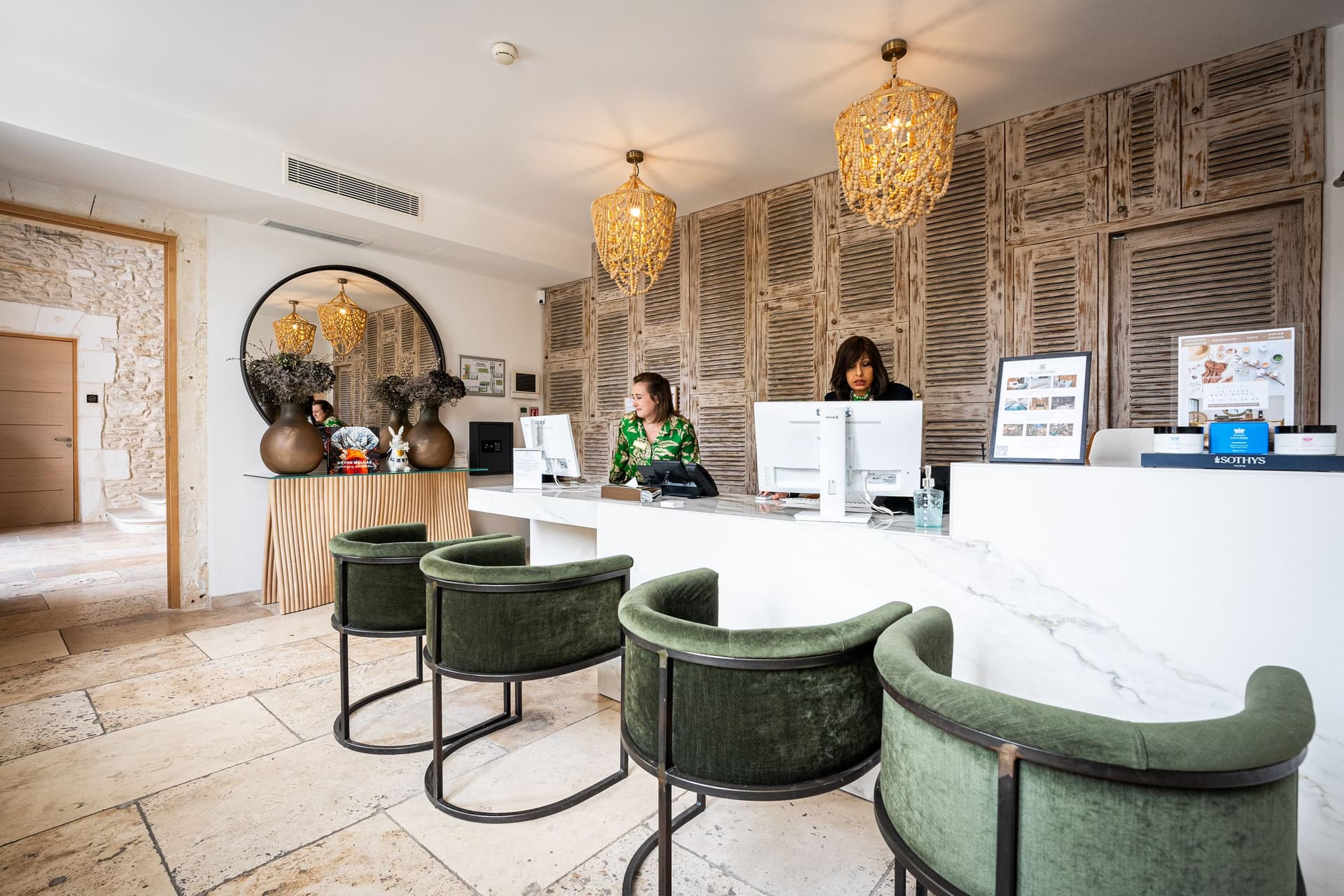 Accueil moderne avec deux réceptionnistes et chaises vertes.