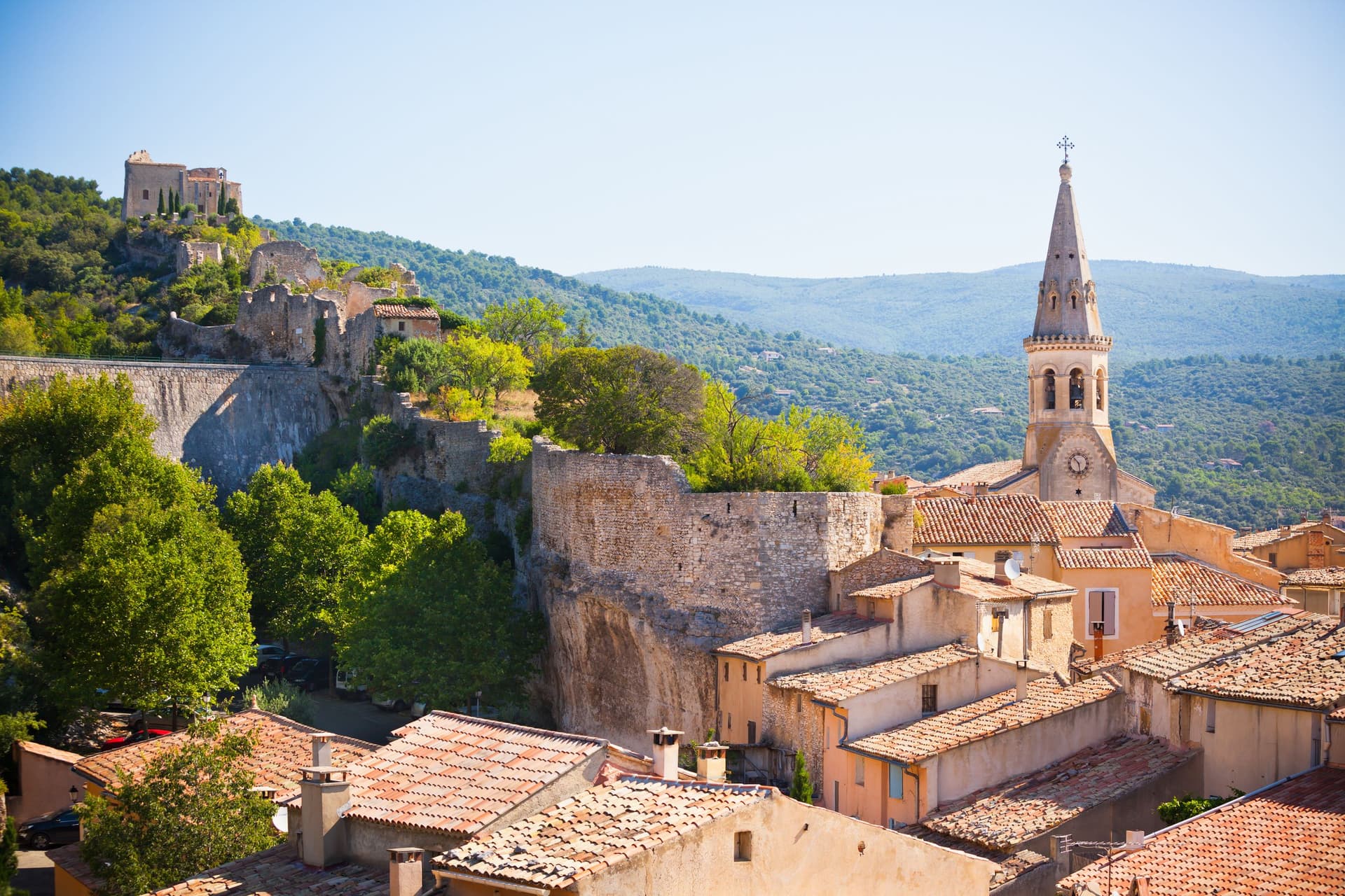 Village provençal avec église et collines verdoyantes.