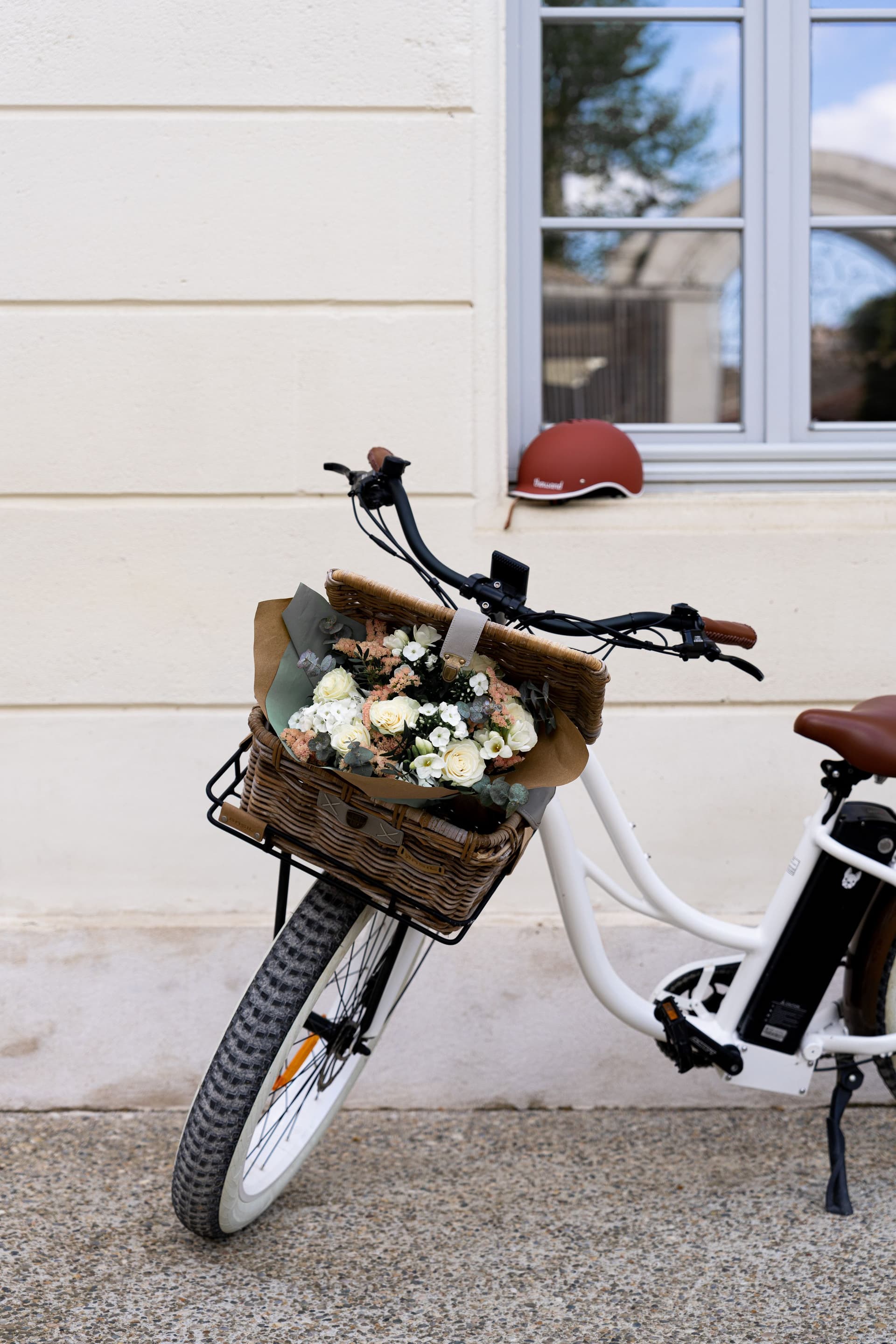 Vélo blanc avec fleurs dans le panier.