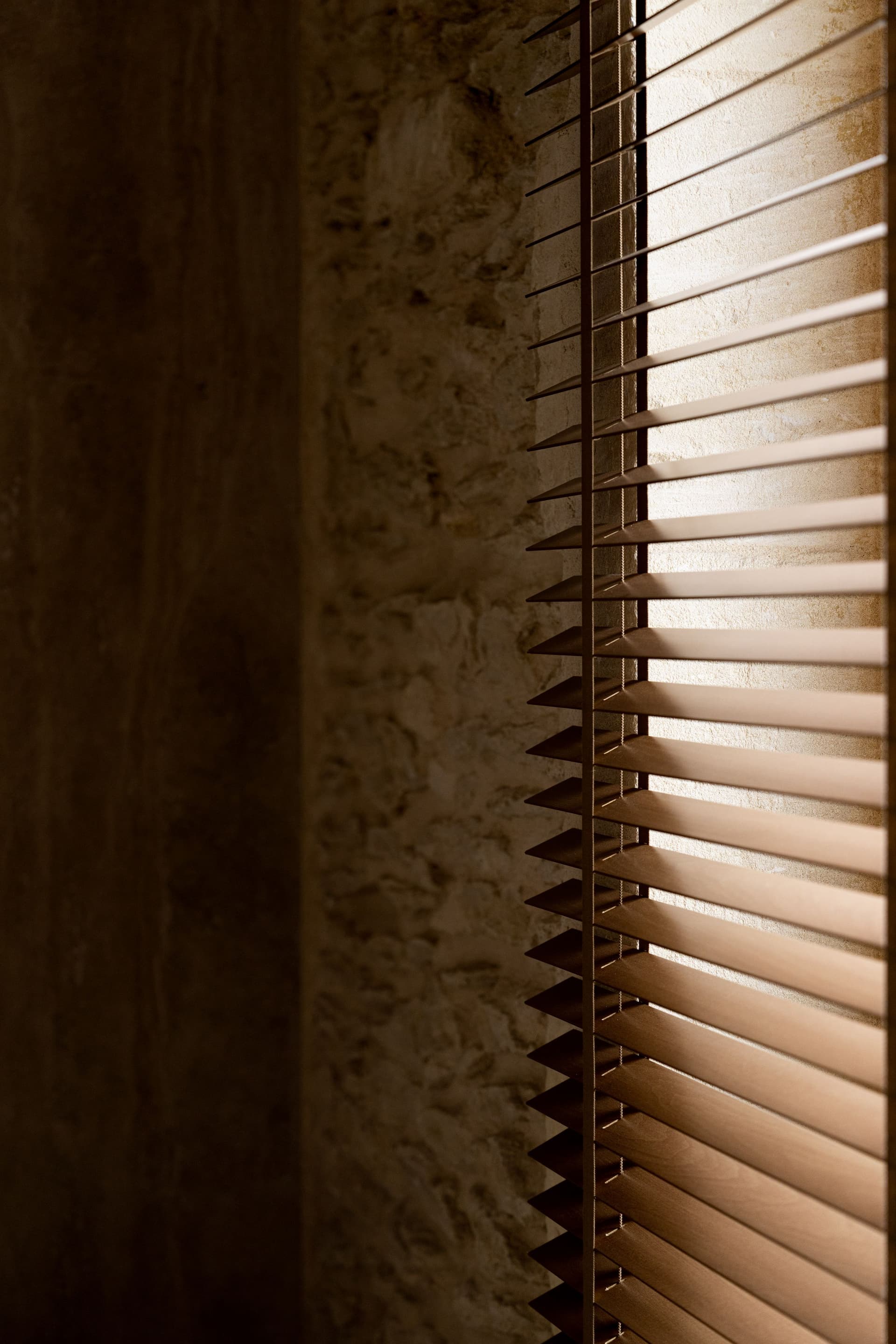 Store en bois devant un mur en pierre.