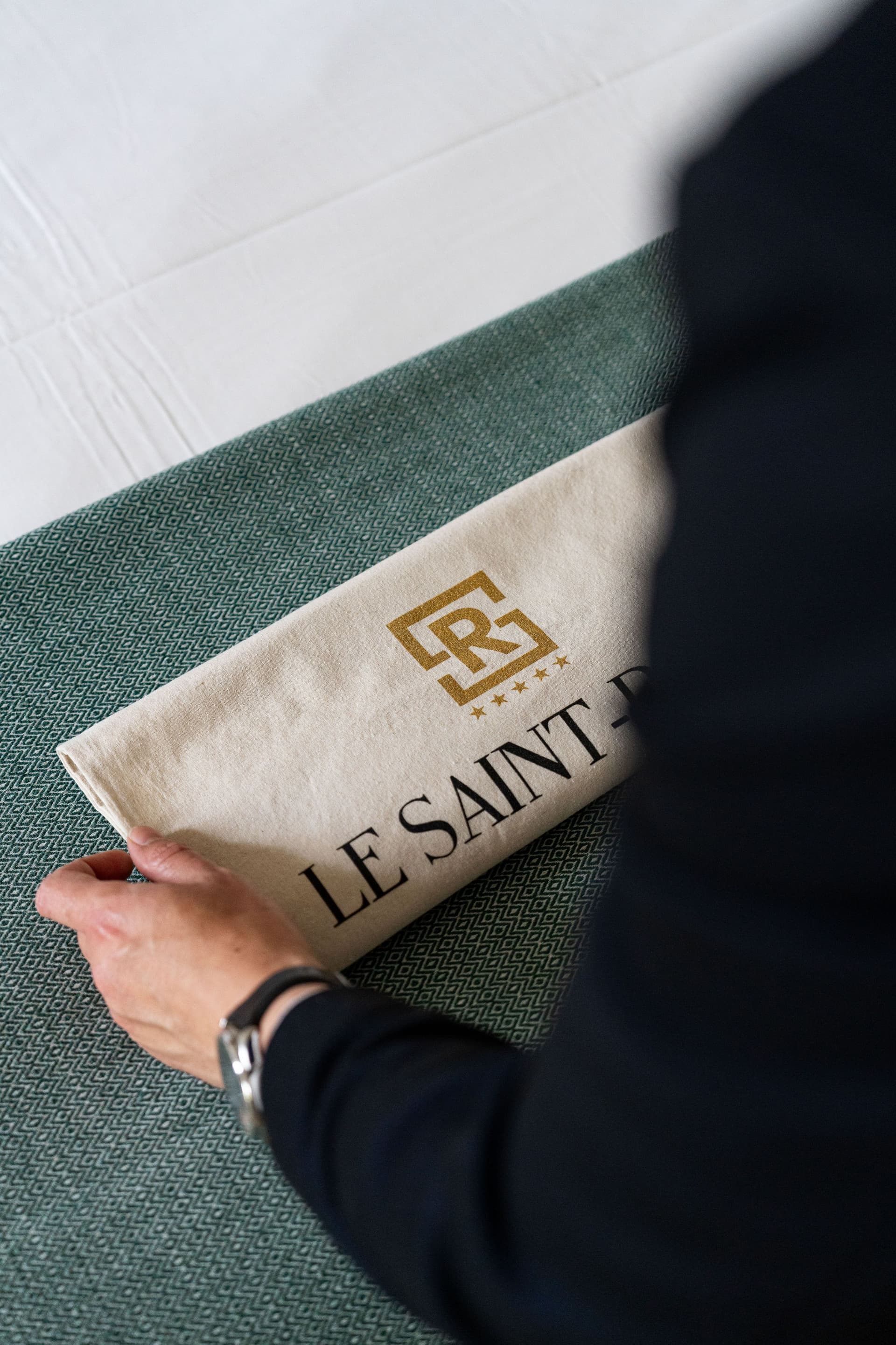 Serviette Le Saint réservé sur un lit.