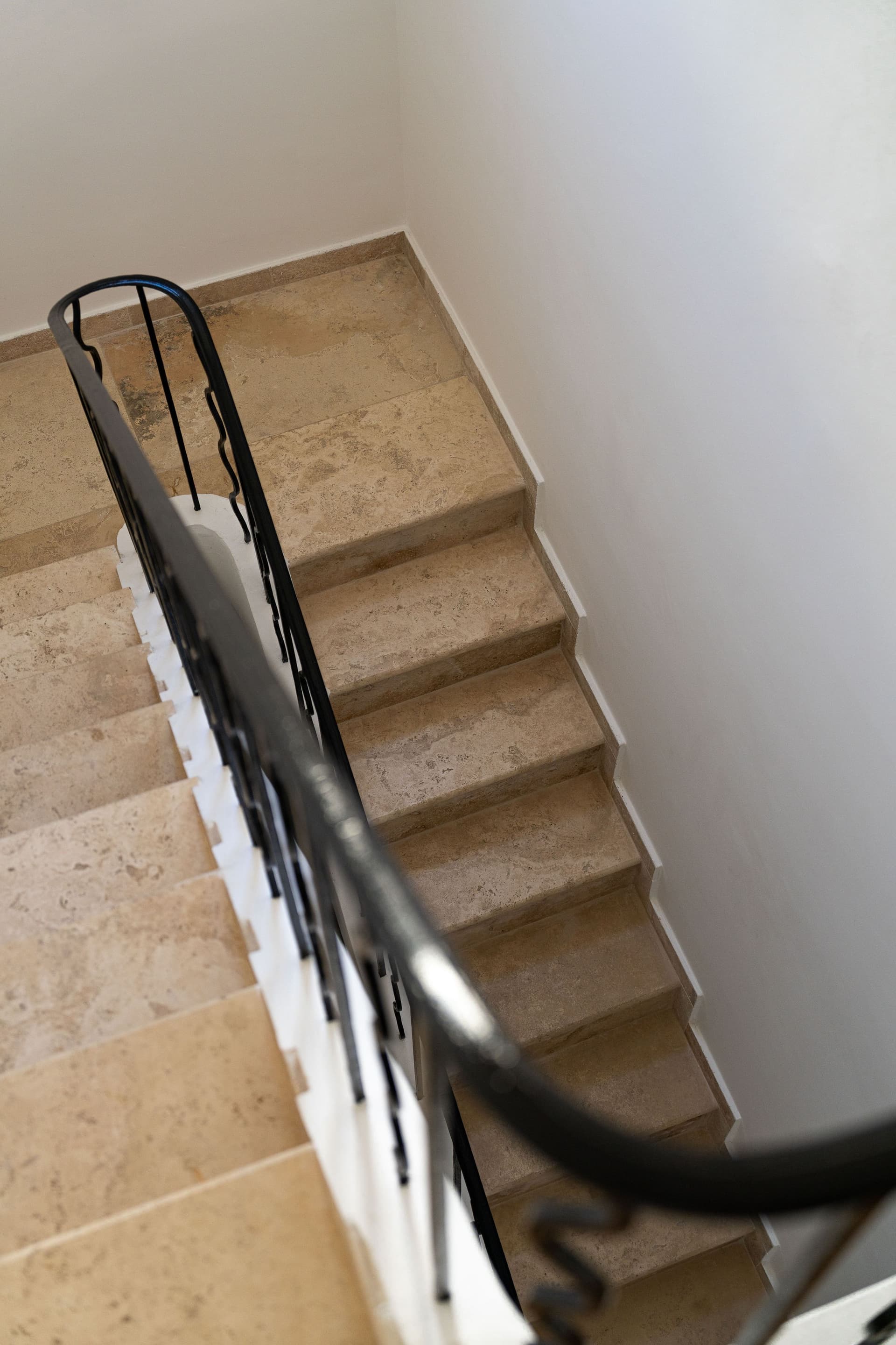 Escalier en pierre avec rampe en métal noir.