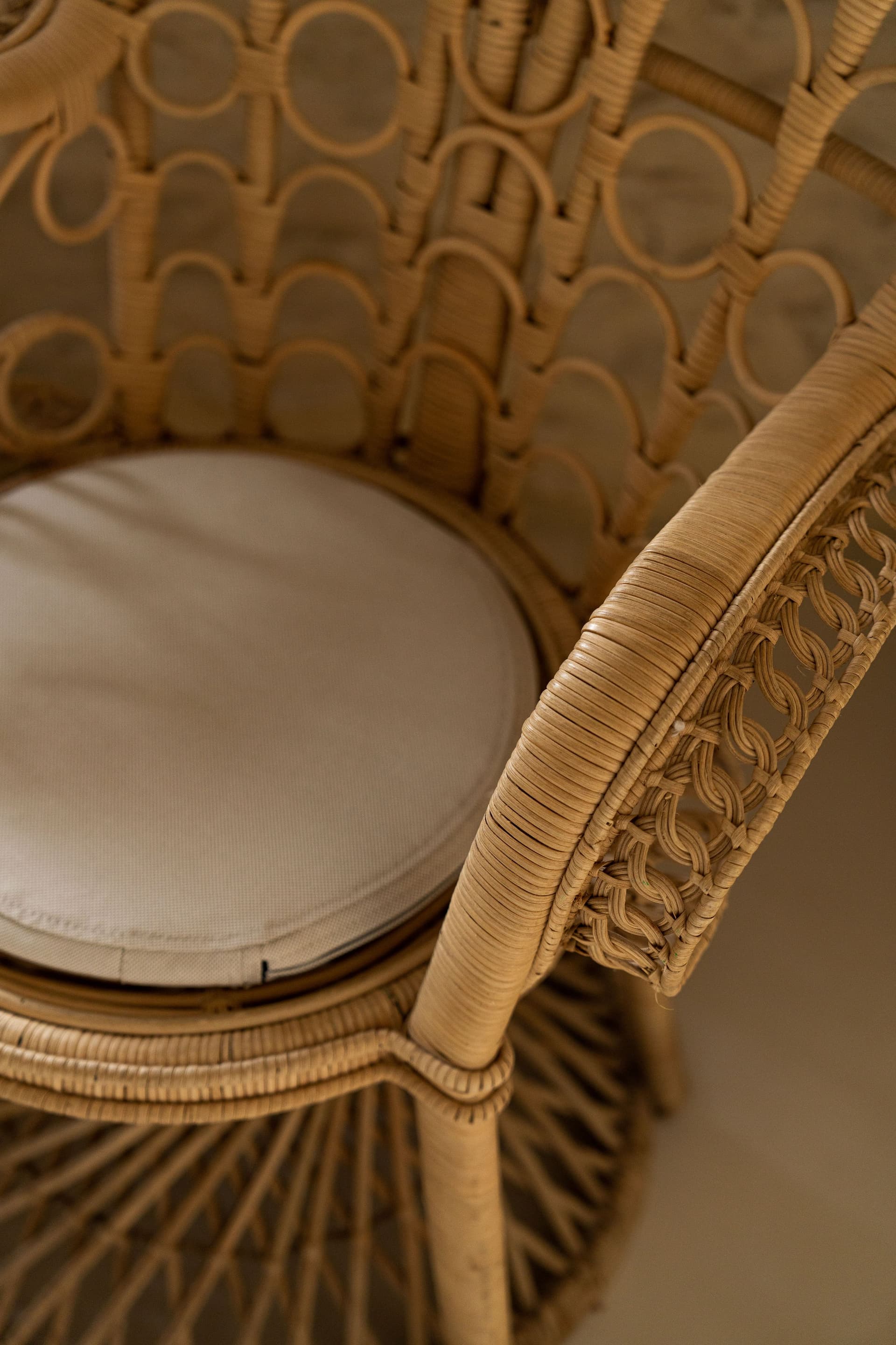 Chaise en rotin avec coussin beige.