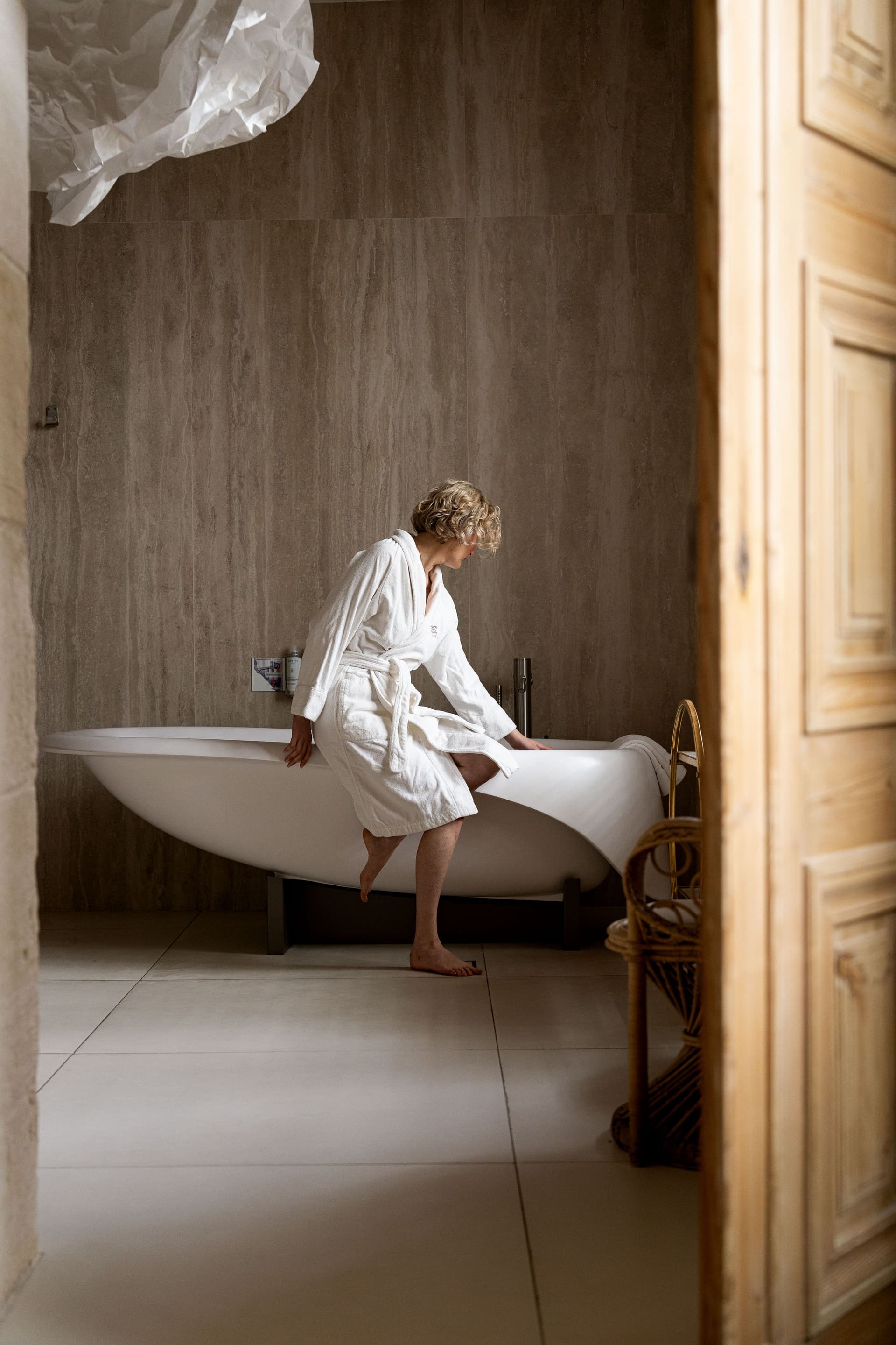 Personne entrant dans une baignoire moderne, peignoir blanc.