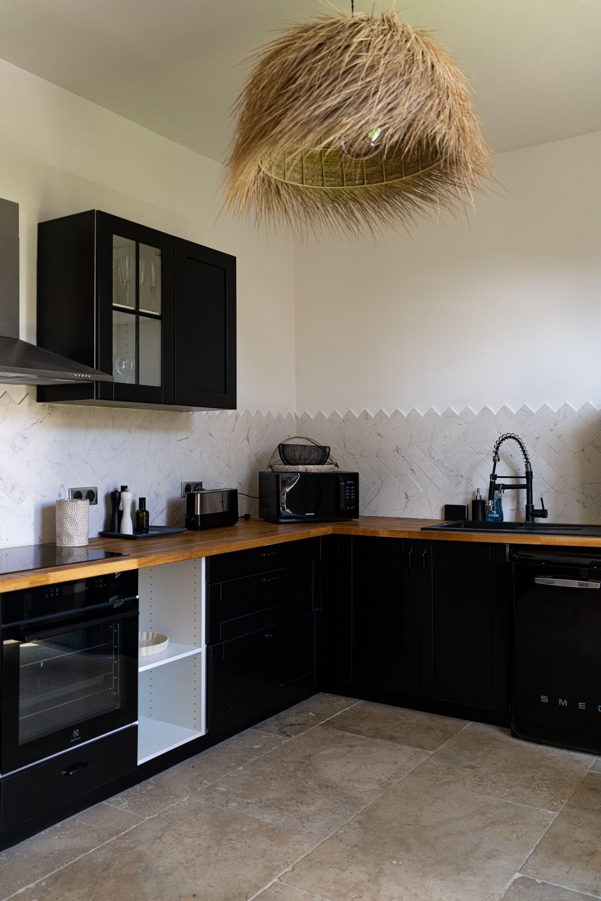 Cuisine moderne avec meubles noirs et éclairage naturel.