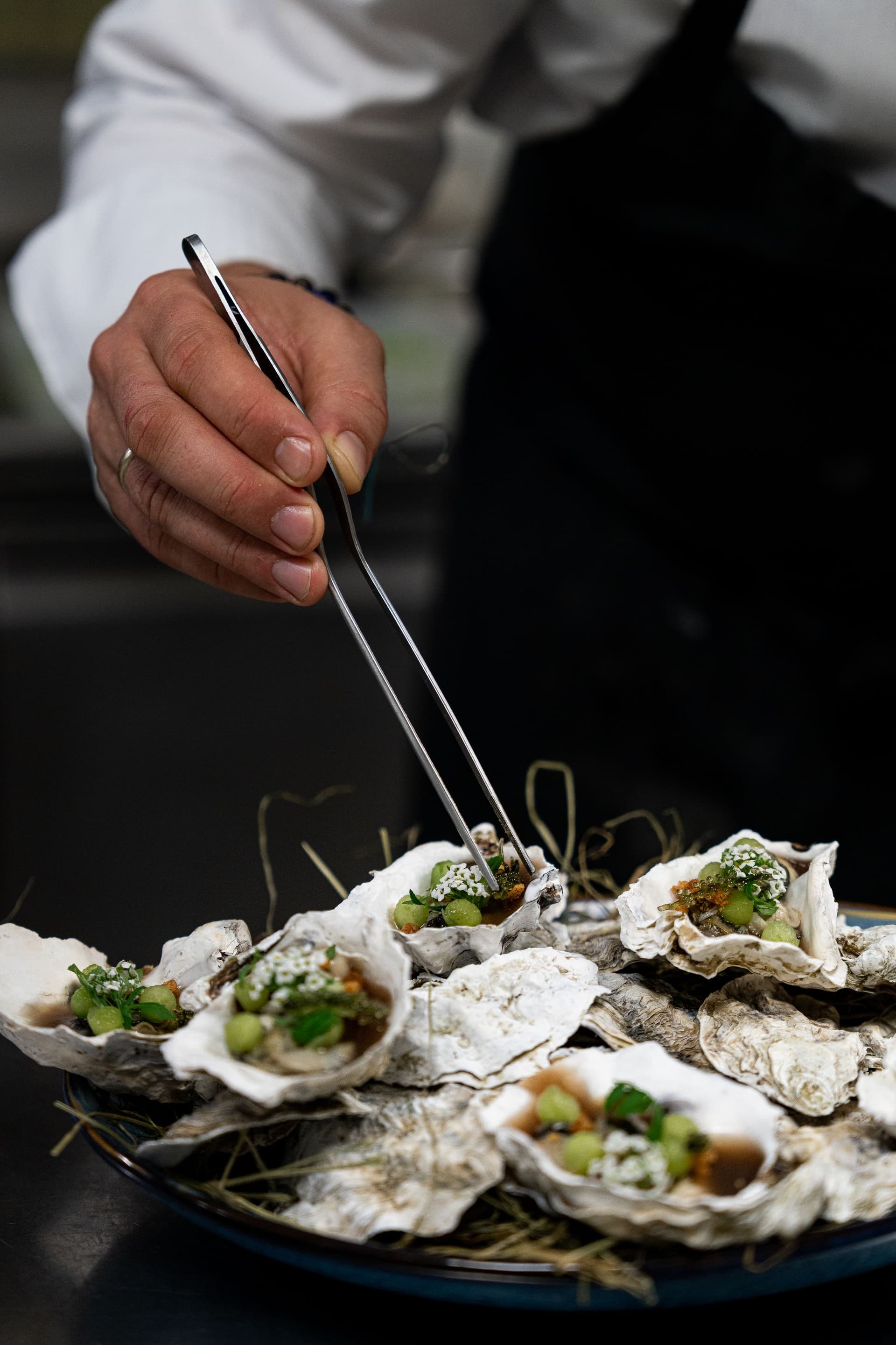 Chef préparant un plat d'huîtres garnies raffinées.