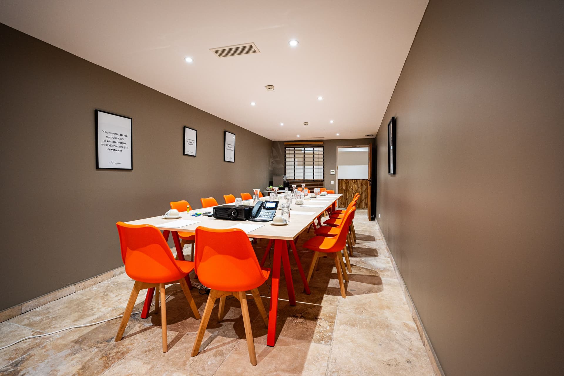Salle de réunion avec chaises orange et table blanche.