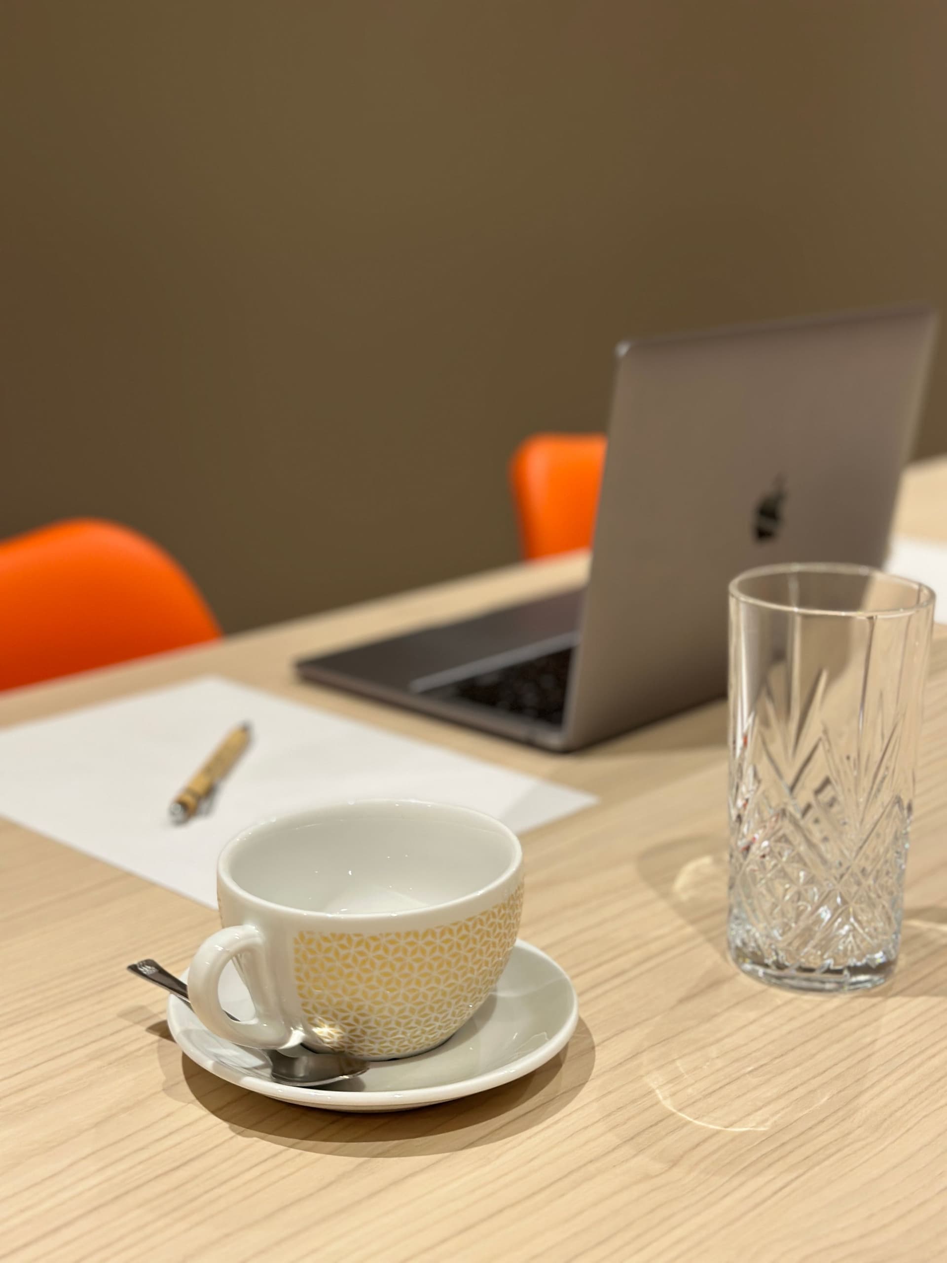 Table avec ordinateur, tasse et verre cristal.