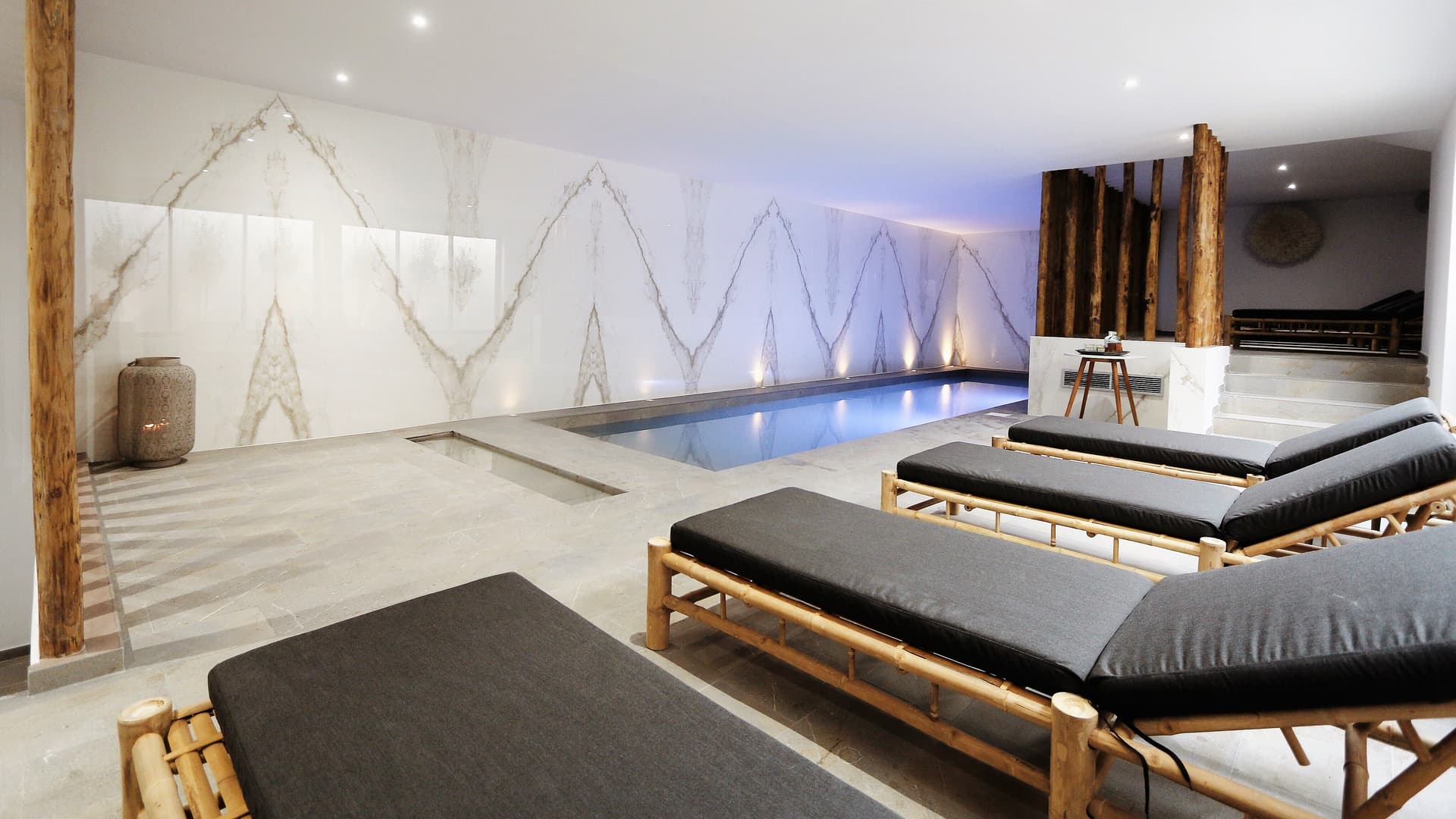 Piscine intérieure avec chaises longues en bois.