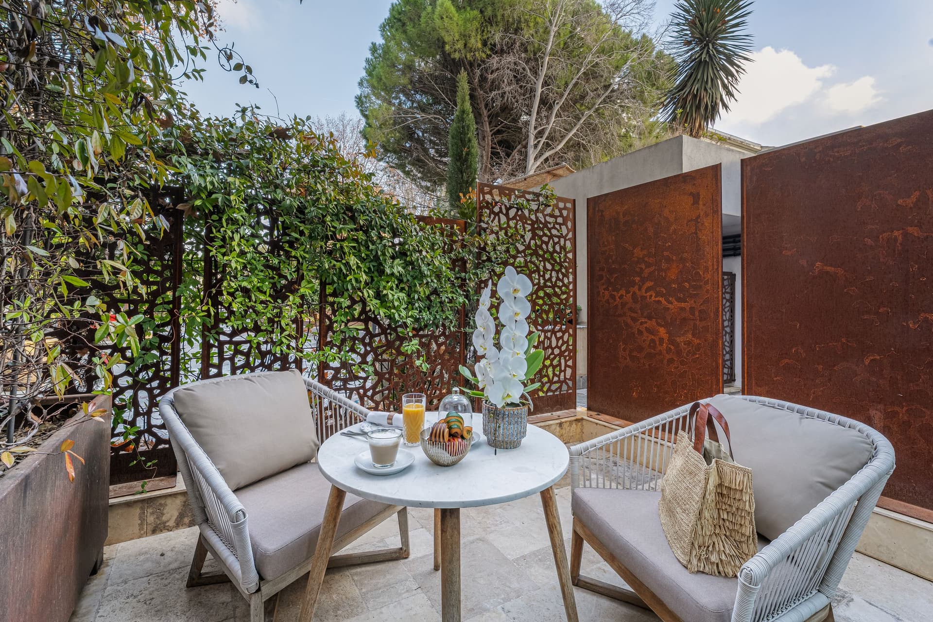 Terrasse avec table, chaises et plantes vertes.