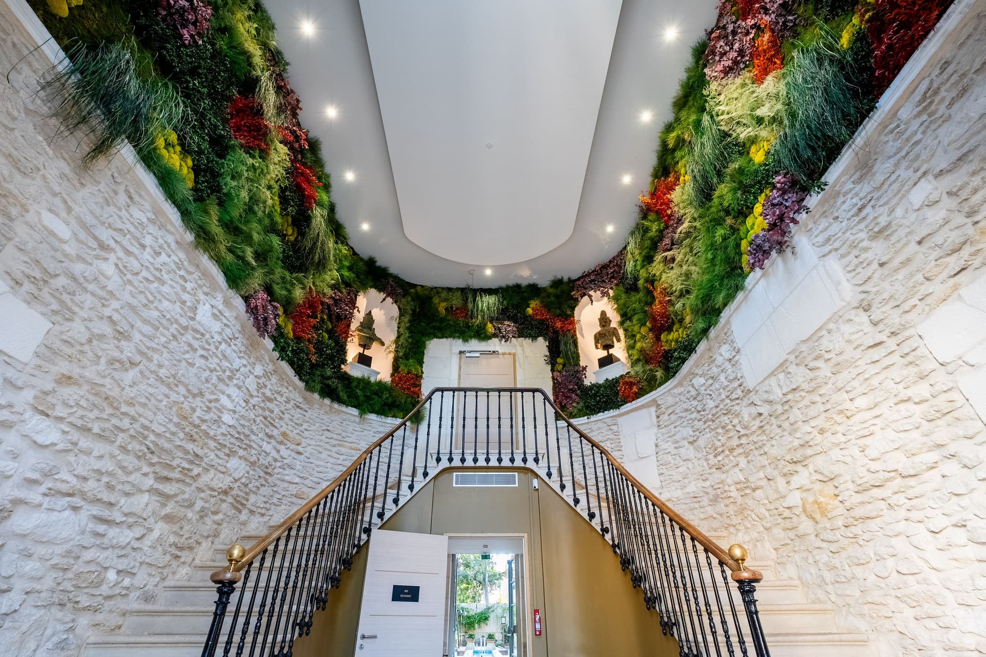 Escalier en pierre avec mur végétal intérieur coloré.