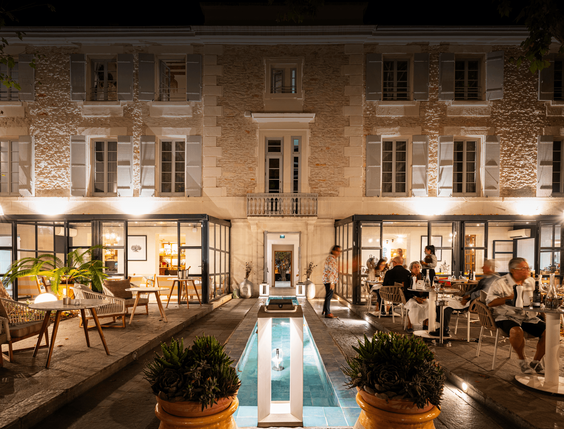 Terrasse de restaurant éclairée devant bâtiment en pierre