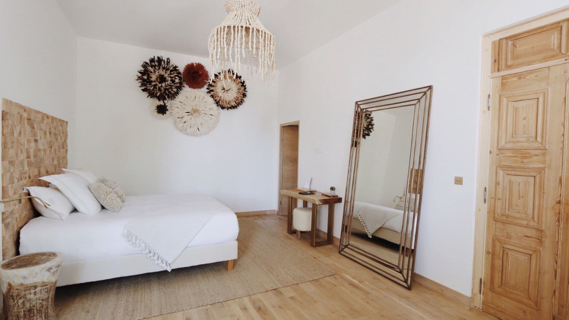 Chambre minimaliste avec miroir et décoration murale artistique.