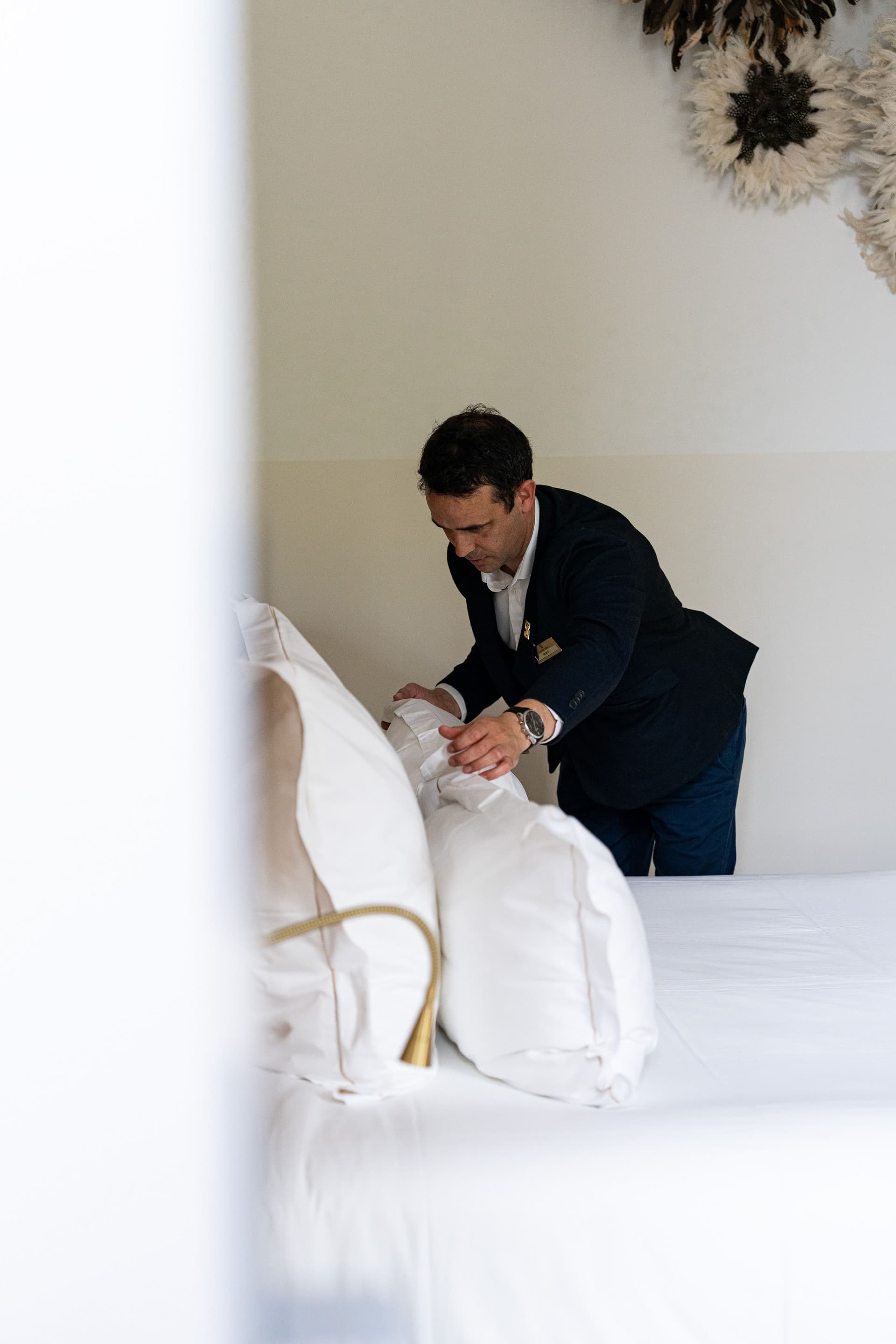 Homme préparant le lit d'une chambre d'hôtel.