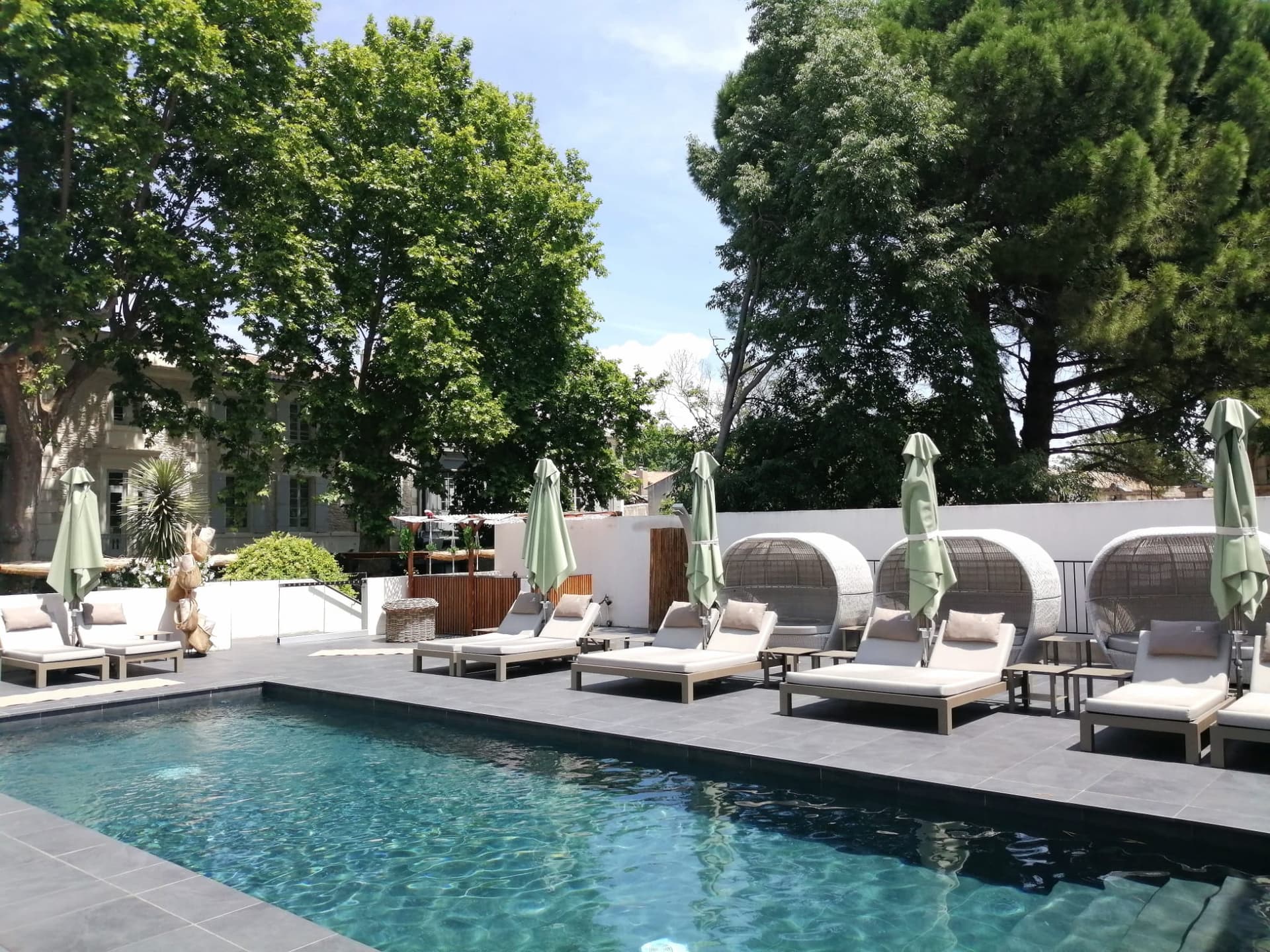 Piscine entourée de chaises longues et arbres.