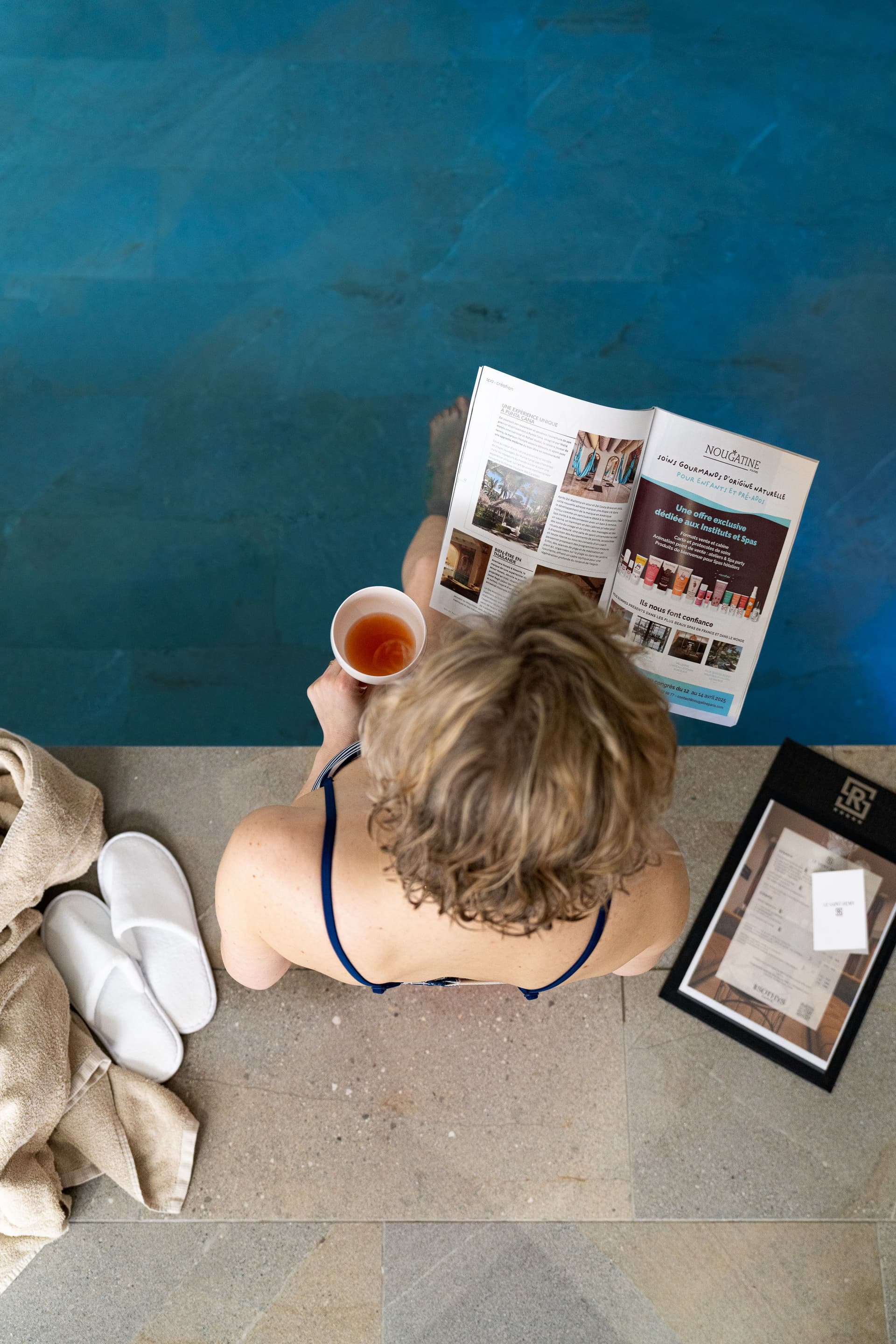 Personne lisant près d'une piscine avec boisson.
