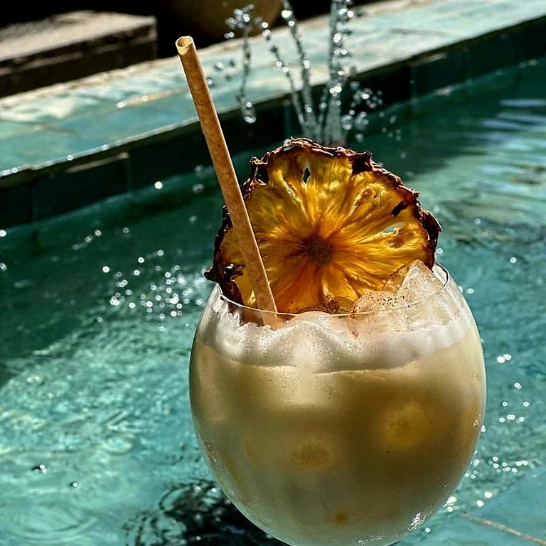 Cocktail tropical avec tranche d'ananas près piscine.