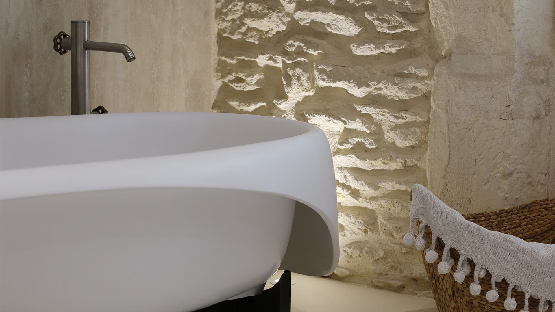 Baignoire moderne avec mur en pierre apparente.
