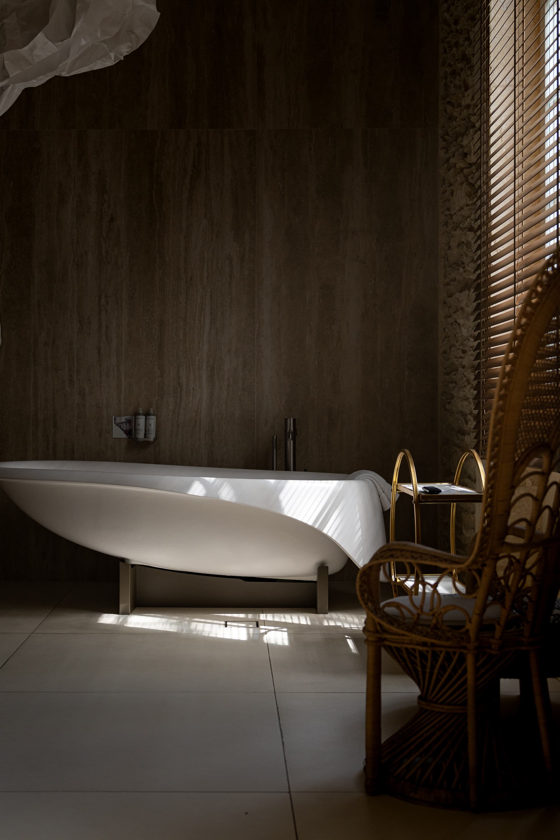 Salle de bain lumineuse avec baignoire et chaise en osier.