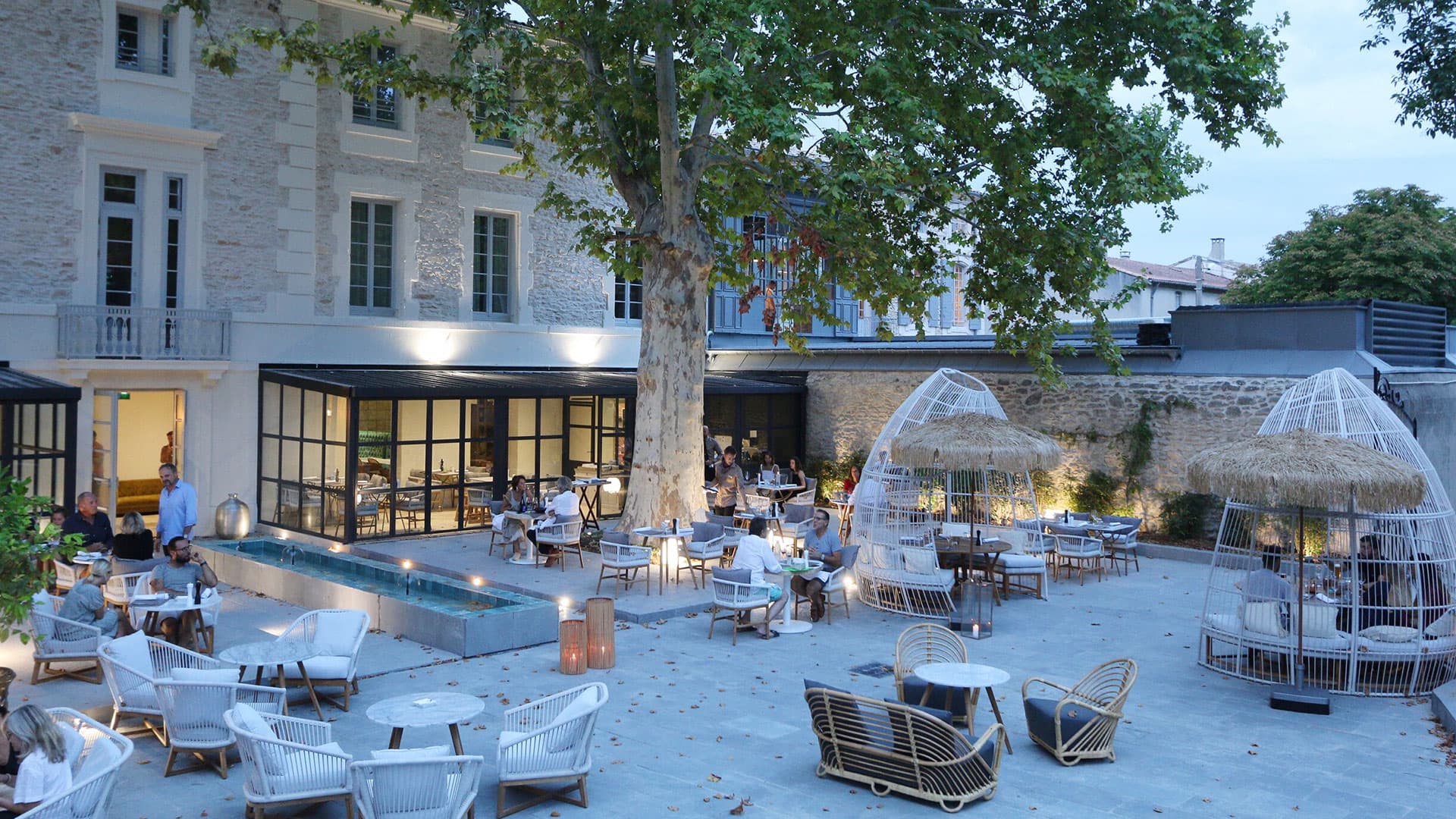 Terrasse de restaurant élégante avec tables extérieures éclairées.