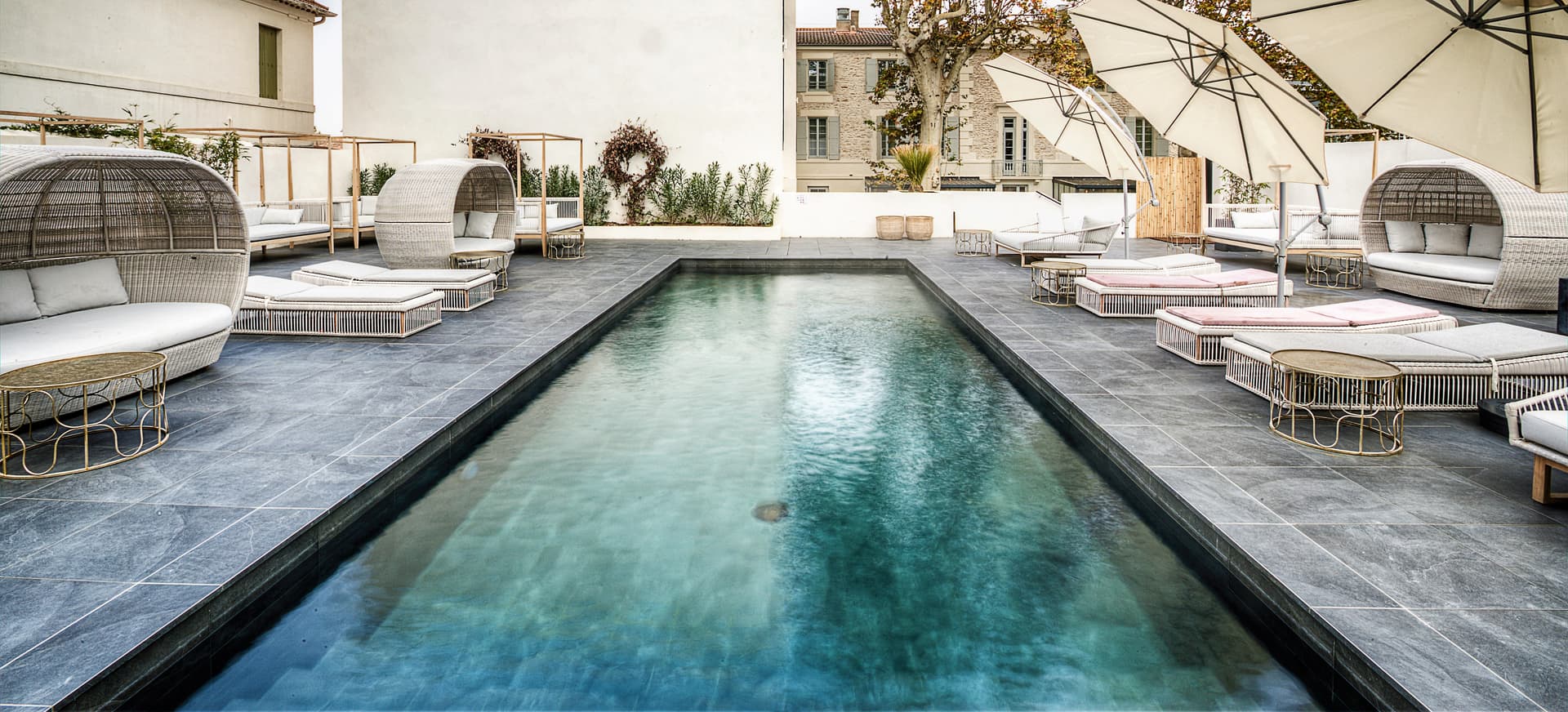 Piscine moderne avec chaises longues et parasols.