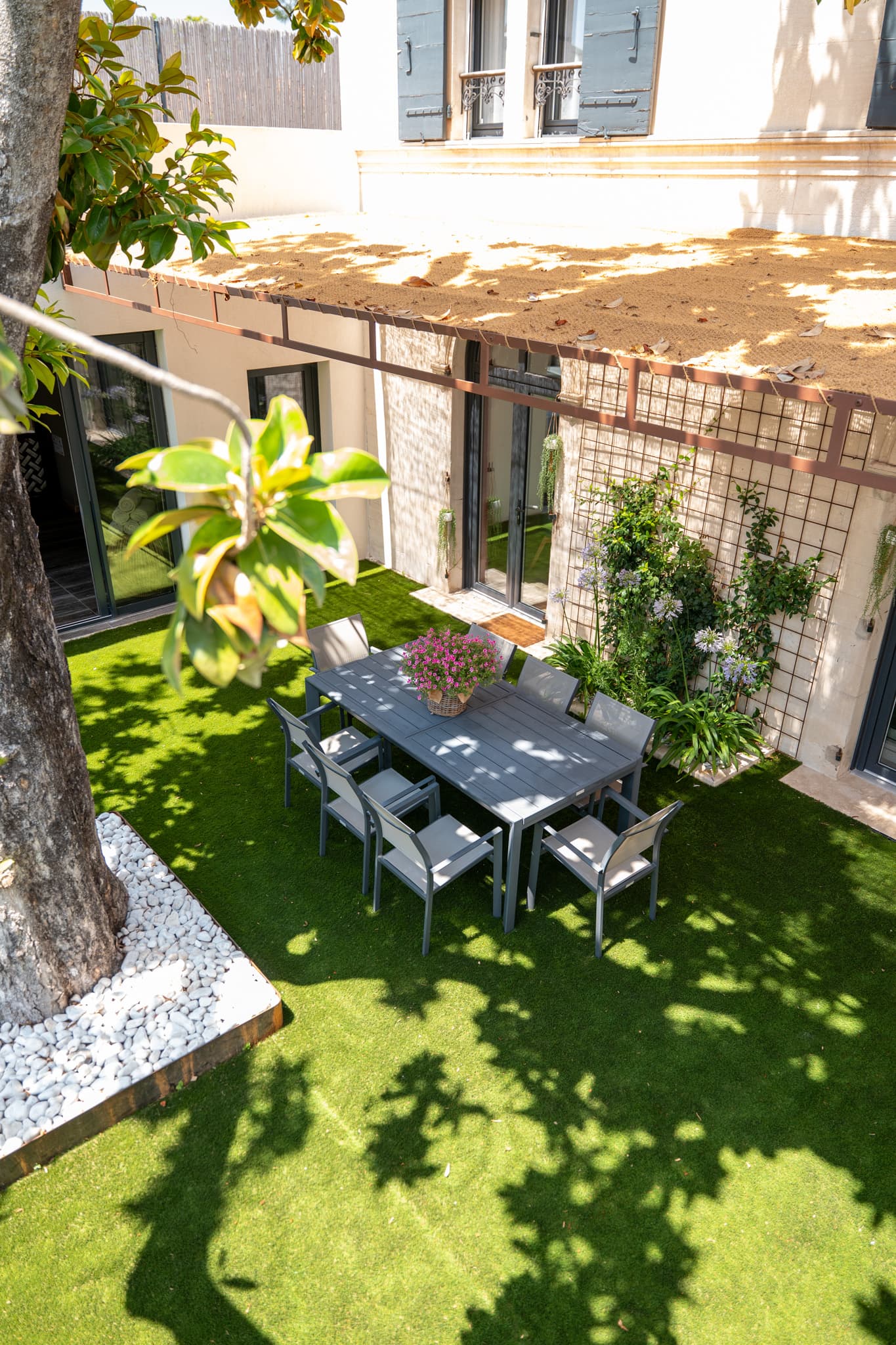 Jardin avec table et chaises sur gazon.